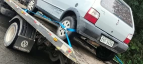 Guincho plataforma transportando um veículo Renault, cor cinza, estacionado em Francisco Morato.