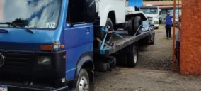 Guincho plataforma azul transportando uma caminhonete branca em Francisco Morato.
