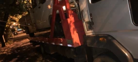 Guincho de plataforma transportando um veículo em Campo Grande, com parte do carro erguida.