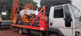 Guincho plataforma transportando um equipamento agrícola laranja em Campo Grande.