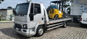 Guincho plataforma prateado transportando um empilhadeira amarela em São José dos Pinhais.