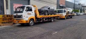 Dois guinchos de plataforma estacionados em Belém, um com um SUV cinza e outro com um carro branco.