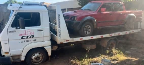 Guincho plataforma transportando uma caminhonete vermelha em Primavera do Leste, estacionado em área externa.