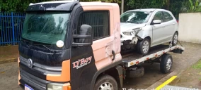 Guincho plataforma em Taubaté transportando um carro prata com danos na frente.