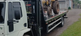 Guincho de plataforma transportando uma máquina agrícola em Bom Princípio, estacionado em uma rua.