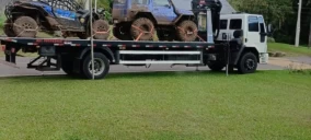 Guincho plataforma estacionado em Bom Princípio, transportando um veículo off-road com rodas sujas.