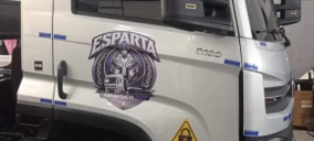 Imagem de um caminhão guincho estacionado, com adesivo da marca "Esparta" visível, em ambiente interno.