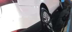 Guincho plataforma em Caruaru transportando veículo branco com roda erguida.