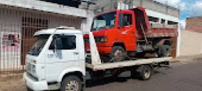 Guincho plataforma transportando um caminhão vermelho em Contagem, estacionado em uma rua.