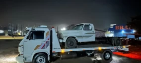 Guincho plataforma em Rio do Sul transportando uma caminhonete branca, estacionado à noite.