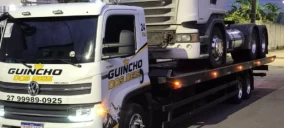 Guincho plataforma transportando um caminhão na cidade de Serra, estacionado em uma rua.