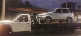 Guincho plataforma transportando um veículo SUV prata em Ubatuba, com motorista visível no caminhão.