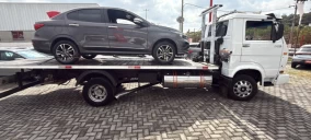 Guincho plataforma em Betim transportando um carro cinza sobre a carroceria.