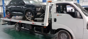 Guincho plataforma transportando um veículo SUV preto em uma oficina no Rio de Janeiro.
