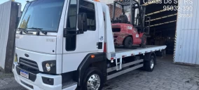 Guincho plataforma branco estacionado em Caxias do Sul, transportando um empilhadeira vermelha.