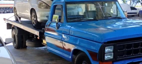 Guincho plataforma azul transportando um veículo prata em São Roque.