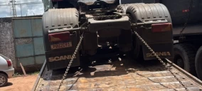 Guincho plataforma em Castanhal transportando caminhão Scania com rodas erguidas, preso por correntes.