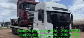 Guincho plataforma transportando caminhão vermelho e branco em área aberta em Castanhal.