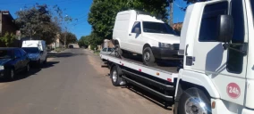 Guincho plataforma em Bauru transportando uma van branca em uma rua residencial.