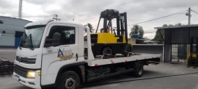 Guincho plataforma transportando empilhadeira amarela em Japeri, estacionado em área com edificações ao fundo.