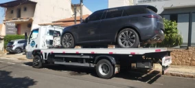 Guincho plataforma estacionado em Indaiatuba, transportando um veículo SUV preto.