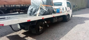Guincho plataforma estacionado em Praia Grande, transportando carga coberta com lona.