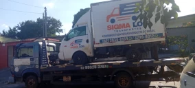 Guincho plataforma transportando um caminhão branco com baú em Goiânia, estacionado em área urbana.