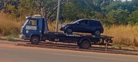 Guincho plataforma em Goiânia transportando um carro preto, estacionado ao lado da rua.